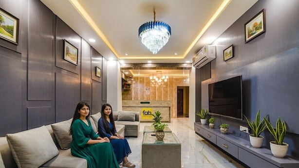 A modern living room with a sofa set, a coffee table, a TV, and decorative plants. - FabHotel Icon (Danapur)