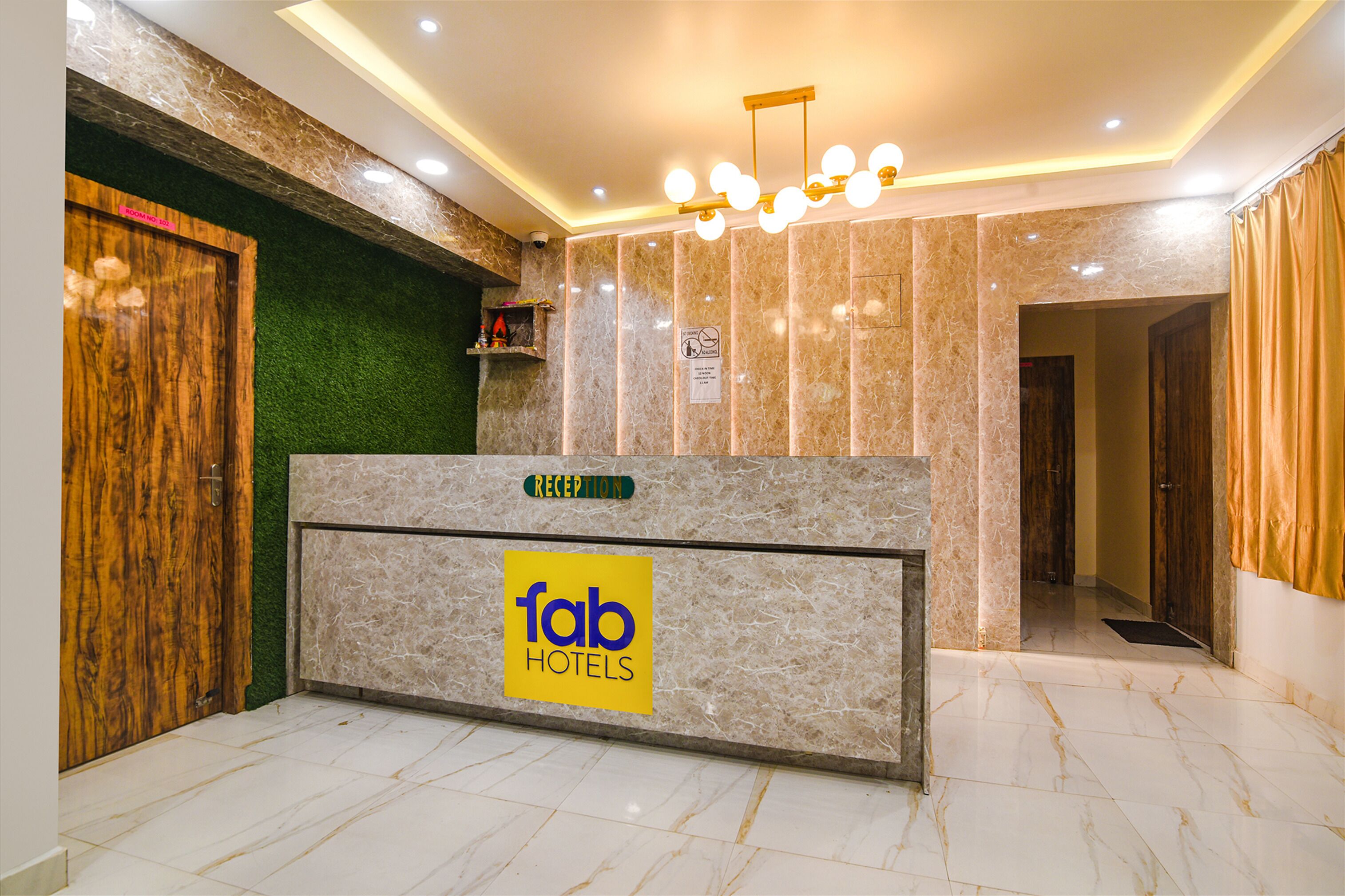 A reception desk with a marble finish, a 'fab hotels' sign, and a green wall with a 'reception' sign above it.