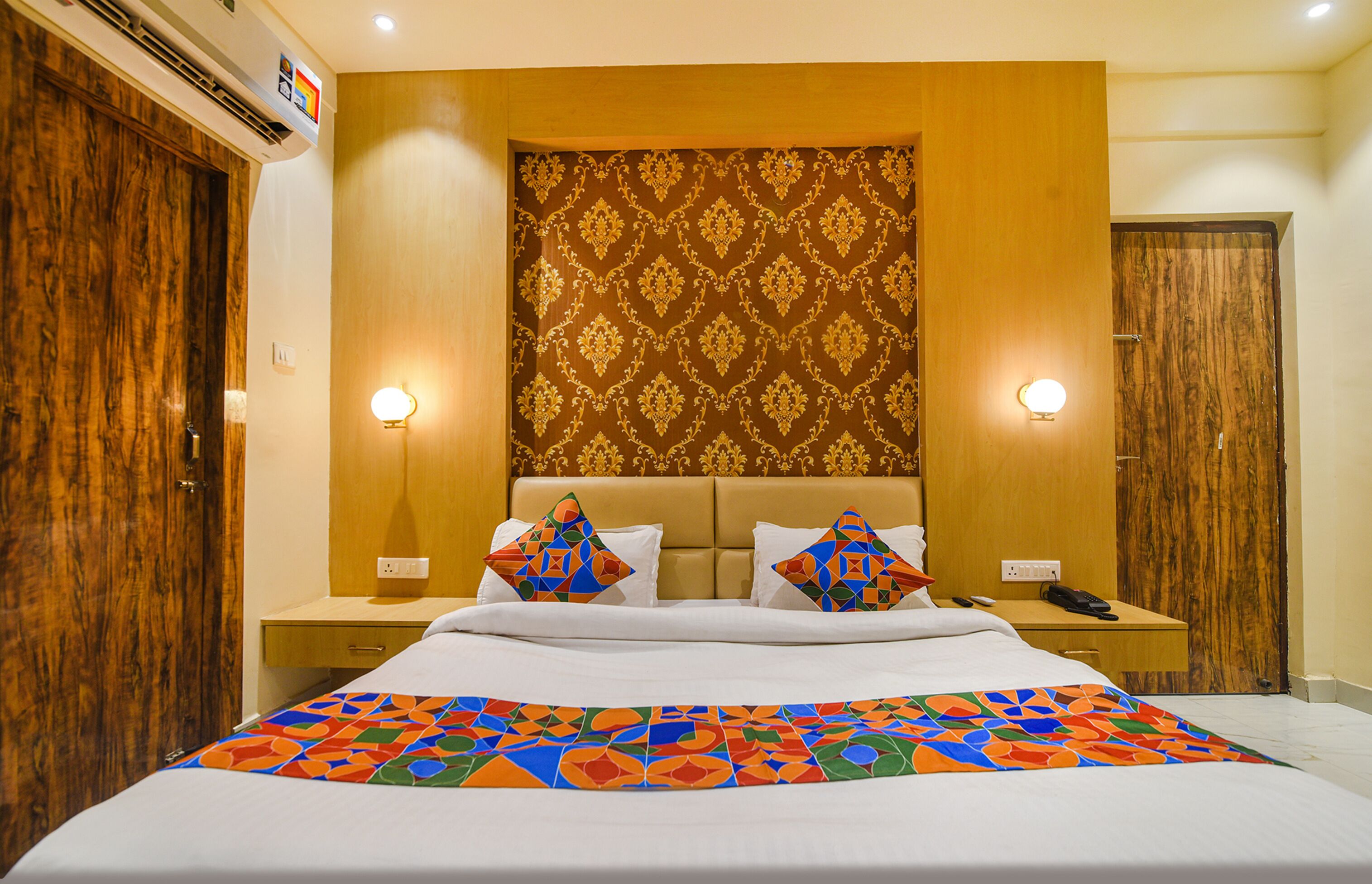 A hotel room with a large bed, wooden wardrobe, and two bedside lamps.