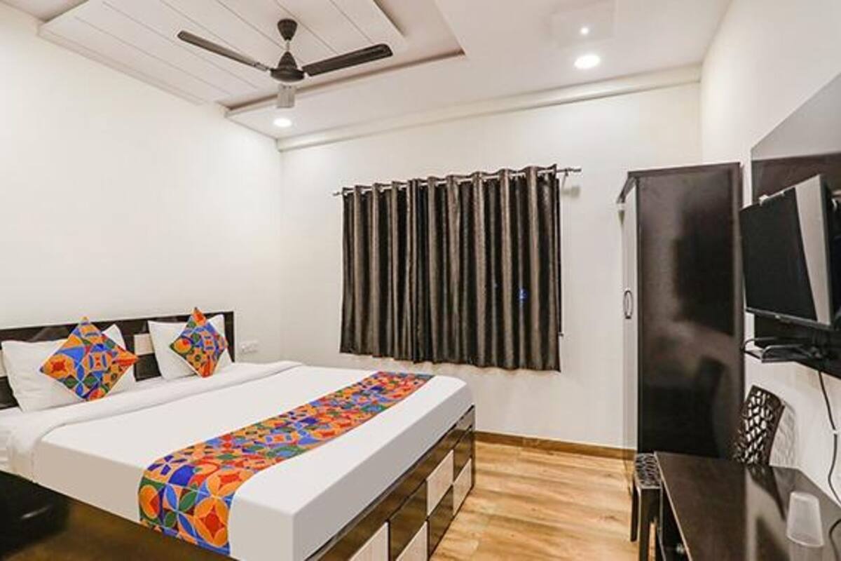 Une chambre d’hôtel équipée d’un lit, d’un bureau, d’une télévision et d’un ventilateur de plafond.