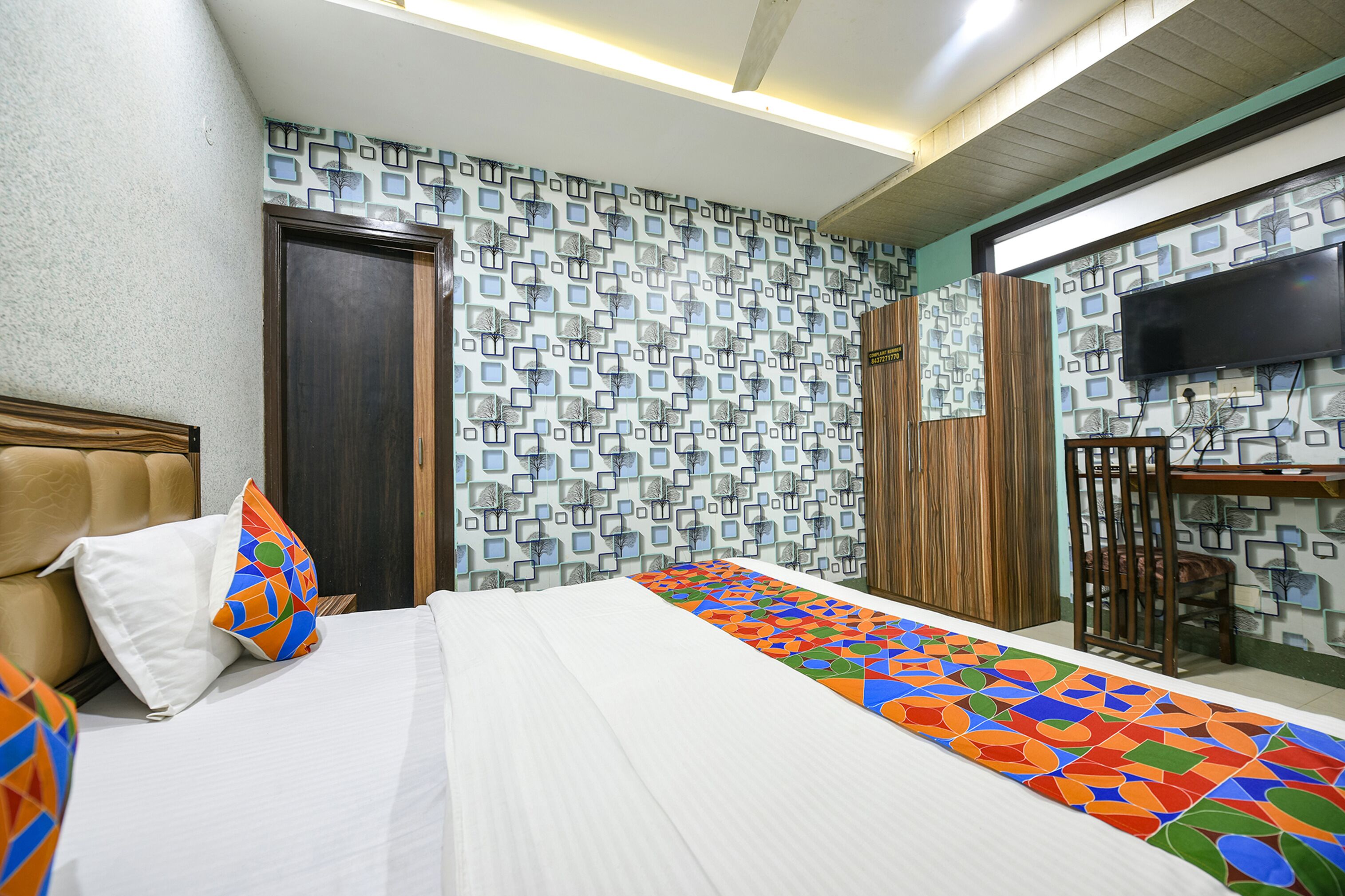A hotel room with a bed, a TV, and a patterned wall.