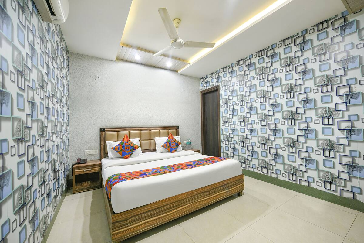 A modern hotel room with a large bed, a ceiling fan, and patterned walls.