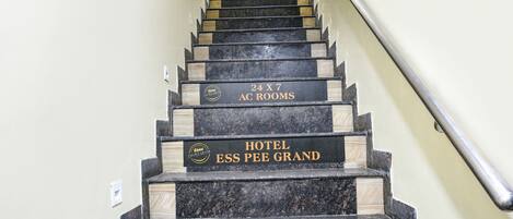 Una escalera con indicaciones que dicen "Habitaciones con aire acondicionado 24 horas" y "Hotel Ess Pee Grand".