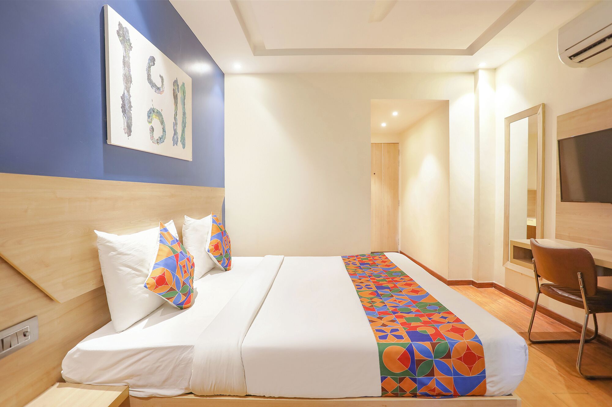 A hotel room with a bed, a desk, and a TV.