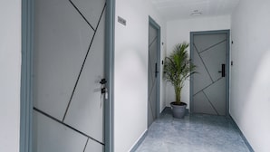 Un pasillo con dos puertas, una que indica 'STAFF ONLY' y la otra con una cerradura. Una planta en maceta se encuentra ubicada entre las puertas.