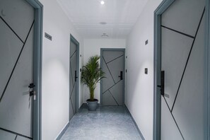 Corridors feature a potted plant and doors leading to various rooms.