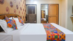 A hotel room with a bed, a chair, and a wardrobe. - Fabhotel Galaxy Residency (Pune)