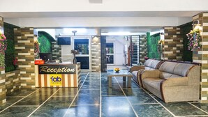 A hotel reception area with a reception desk, a sofa, and a coffee table. - Fabhotel Galaxy Residency (Pune)