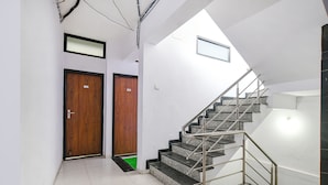 Un interior moderno con una escalera, dos puertas de madera y un piso de baldosas.