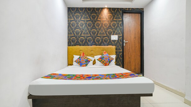 Una cama bien hecha con una colcha estampada, un cabecero y dos almohadas con un diseño geométrico.