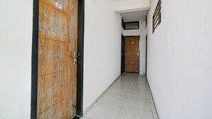 Un pasillo con puertas de madera, paredes blancas y suelo de baldosas.