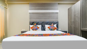 A hotel room with a large bed, a headboard, a wardrobe, and a nightstand. - Fabhotel Classic Inn (Indore)