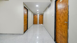 A hallway with two wooden doors, a polished floor, and a ceiling with recessed lighting. - Fabhotel Classic Inn (Indore)