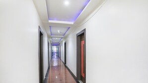 Un long couloir étroit aux murs blancs, doté d’un plancher en bois brun poli et d’un éclairage encastré.