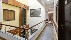A hotel corridor with a marble floor, wooden railings, a large framed picture, and a door marked with the number 203. - FabHotel The Indian (Gurugram)