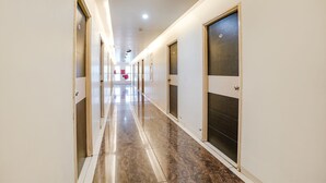 A long, well-lit hallway with doors on both sides, leading to rooms. - Fabhotel Rvg (Vadodara)