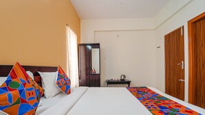 A hotel room with a bed, a desk, a wardrobe, and a mirror. - Fabhotel Sv Home Stay (Tirupati)