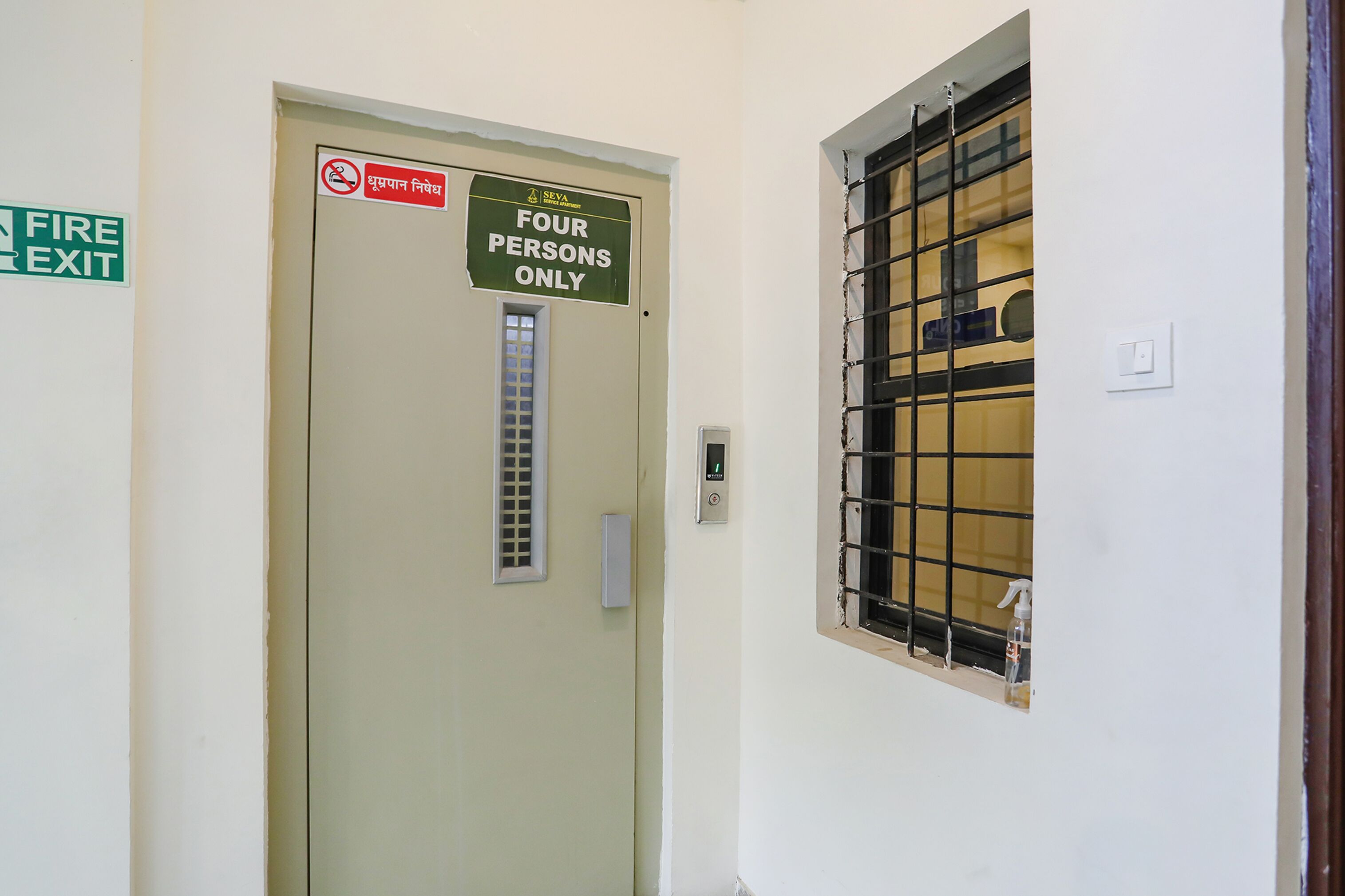A door with a fire exit sign and a sign indicating the door is for four persons only.