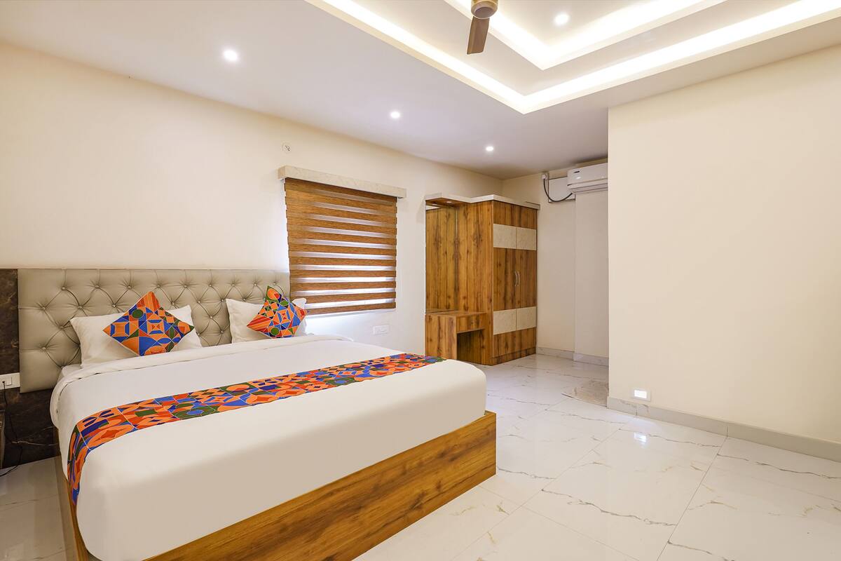 A modern bedroom with a large bed, wooden headboard, and built-in wardrobe.