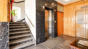 A hotel lobby with a marble staircase, an elevator, a reception desk, and a wooden wall with a 'RESTAURANT' sign. - FabHotel Prime Mayuri Residency - Yadavanahalli (Anekal)