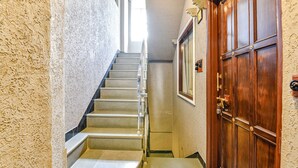 Eine Treppe mit Handlauf, einer Holztür und einem gemusterten Boden.