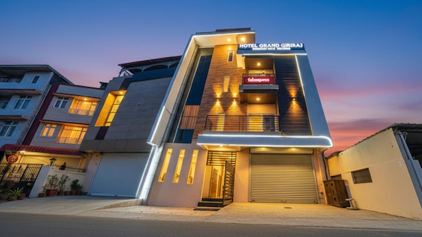 A modern hotel with a prominent sign reading "HOTEL GRAND GIRAJ" and a visible entrance with a closed garage door. - FabHotel Grand Giriraj (Indore)