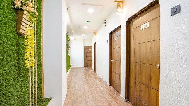 A corridor with wooden doors, a green wall with artificial grass, and a wooden bench with flowers. - Fabhotel 7 Star (Surat)