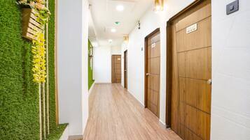 A corridor with wooden doors, a green wall with artificial grass, and a wooden bench with flowers.