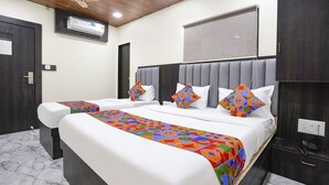 Habitación de hotel con dos camas, ventilador de techo, equipo de aire acondicionado, teléfono y suelo de mármol.