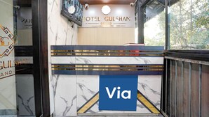 Una mesa de recepción con un letrero que dice 'Via', una cámara de seguridad y un letrero que dice 'HOTEL GULSHAN GRAND'.