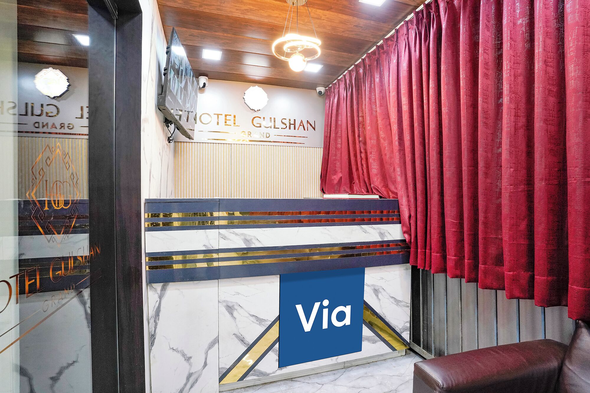 A reception area with a marble counter, a red curtain, and a sign reading 'Via'.