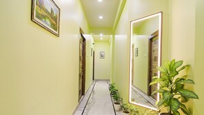 A hallway with a marble floor, green walls, and several potted plants. - FabHotel Nest (Kolkata)