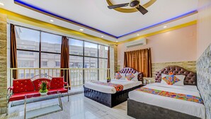 A hotel room with a bed, a red sofa, and a glass coffee table. - FabHotel Nest (Kolkata)