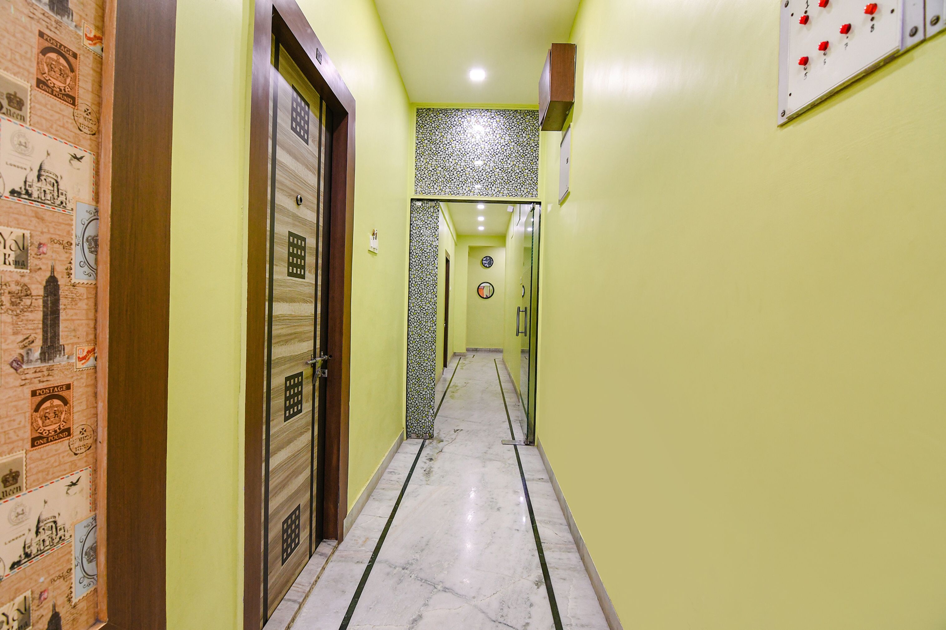 A hallway with a marble floor, a door with a wooden frame, and a wall with a patterned design.