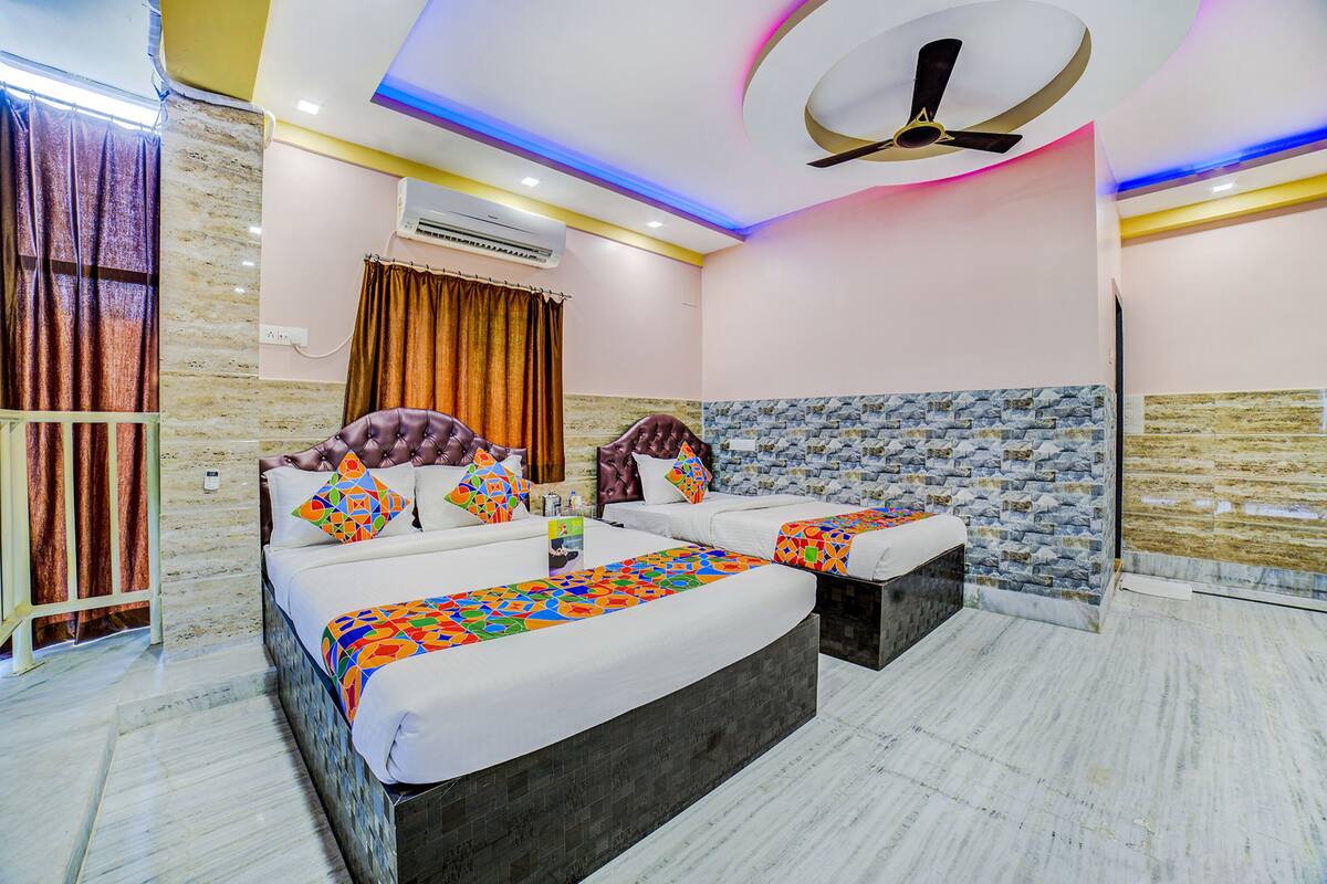 A modern hotel room with a large bed, a separate sofa, a ceiling fan, and a stone accent wall.