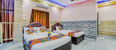 A modern hotel room with a large bed, a separate sofa, a ceiling fan, and a stone accent wall.