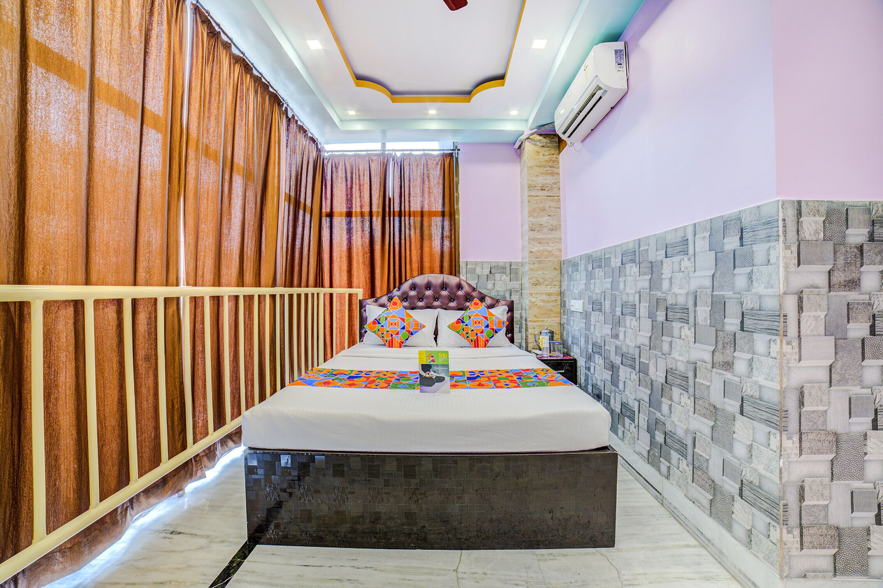 A hotel room with a large bed, a decorative headboard, a nightstand, and a wall with a stone-like pattern.