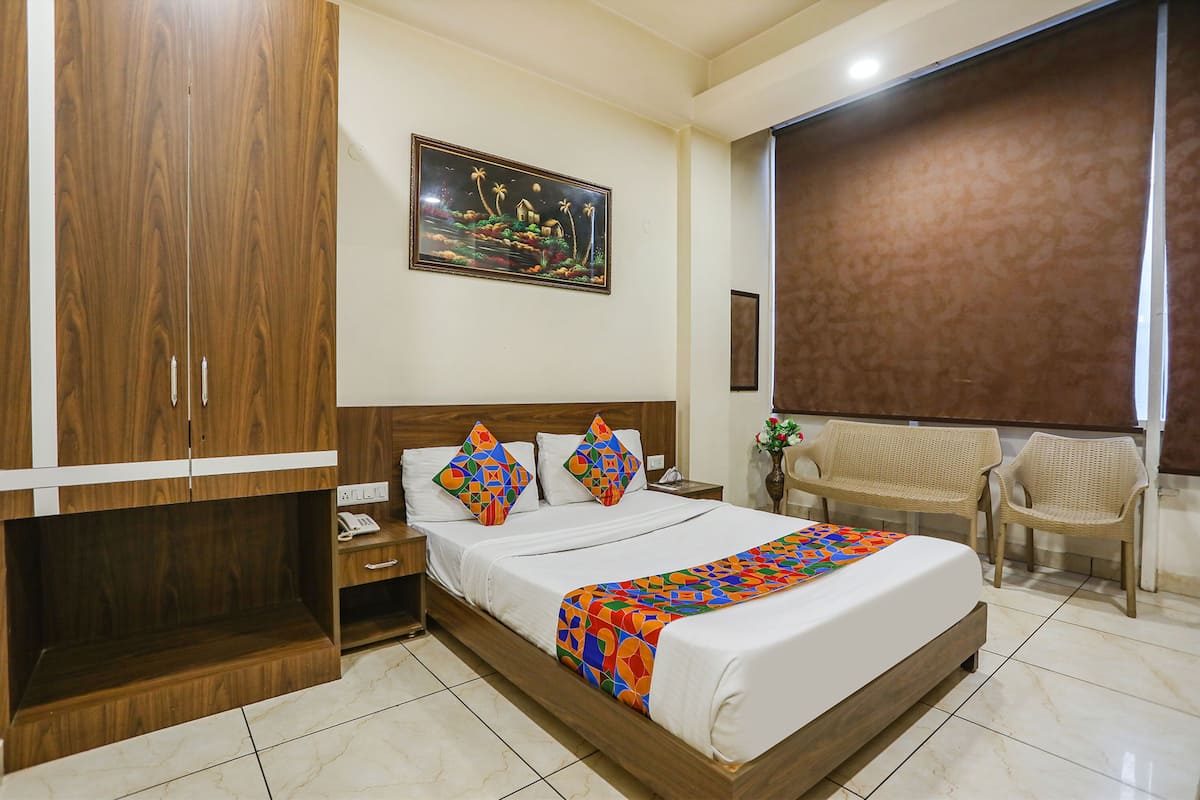 Una habitación de hotel con un armario de madera, una cama con ropa de cama colorida, una mesita de noche y una silla.