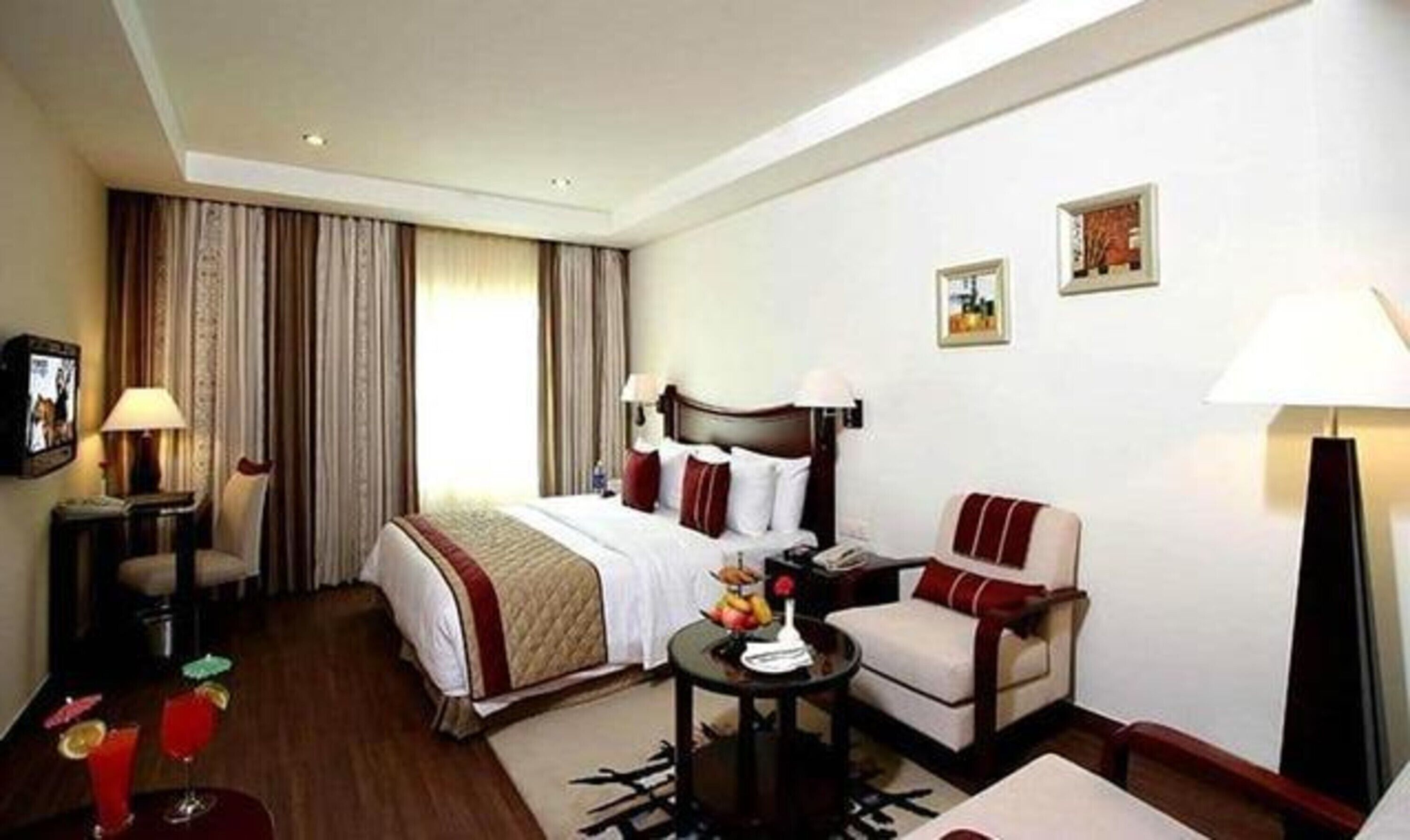 A hotel room with a bed, a chair, a small table, a lamp, and a picture on the wall.
