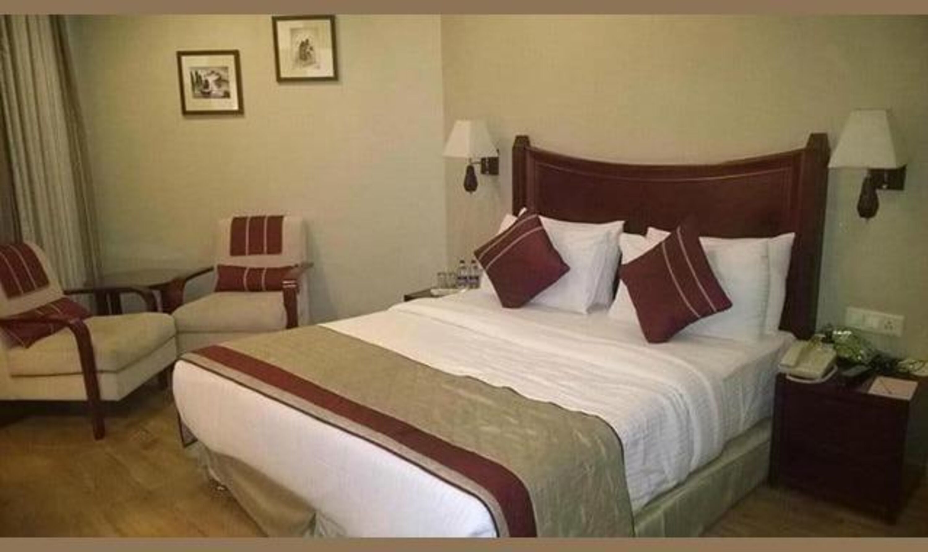 A hotel room with a large bed, two bedside tables, a chair, and two wall-mounted lamps.