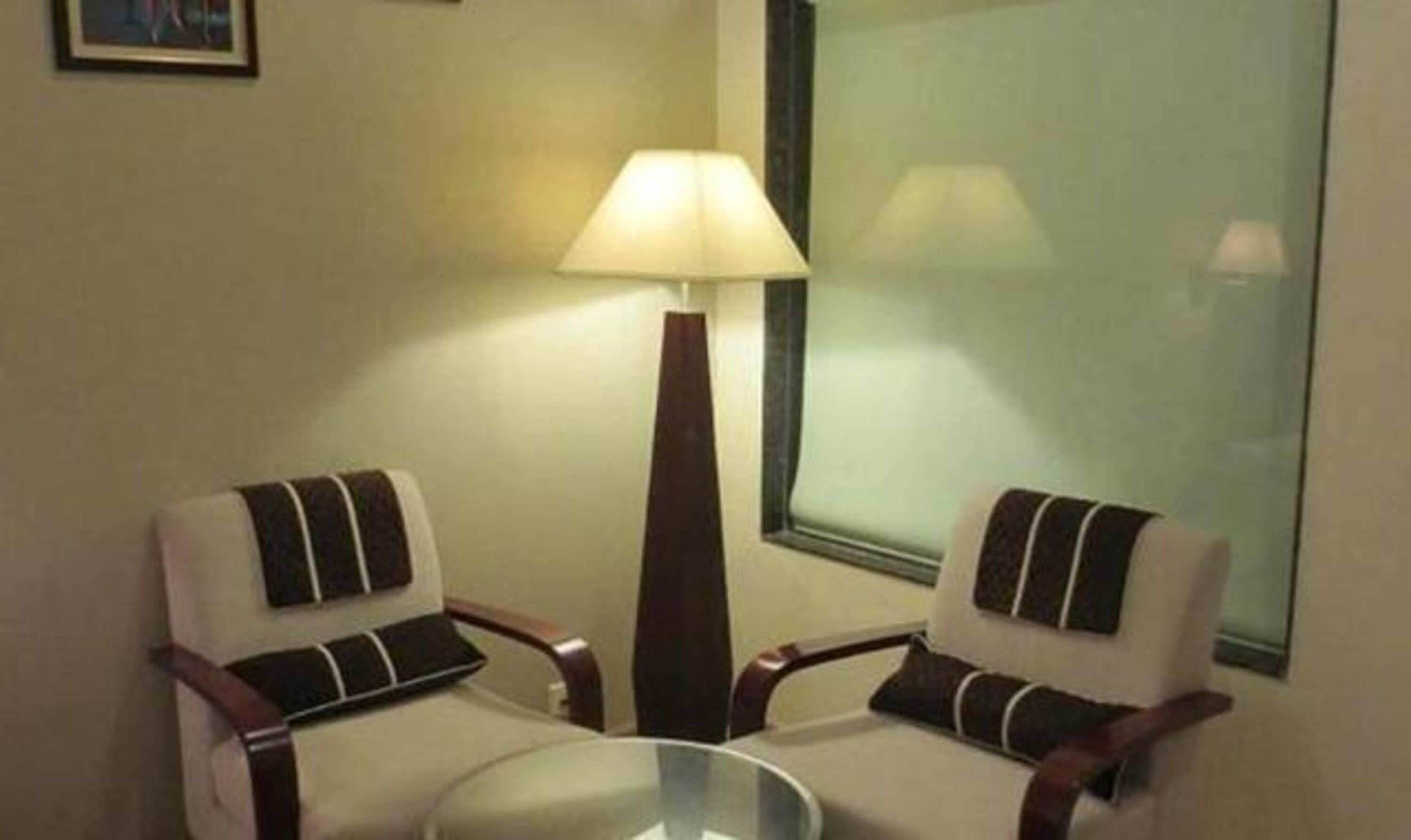 A room with two chairs and a table, a floor lamp, and a window.