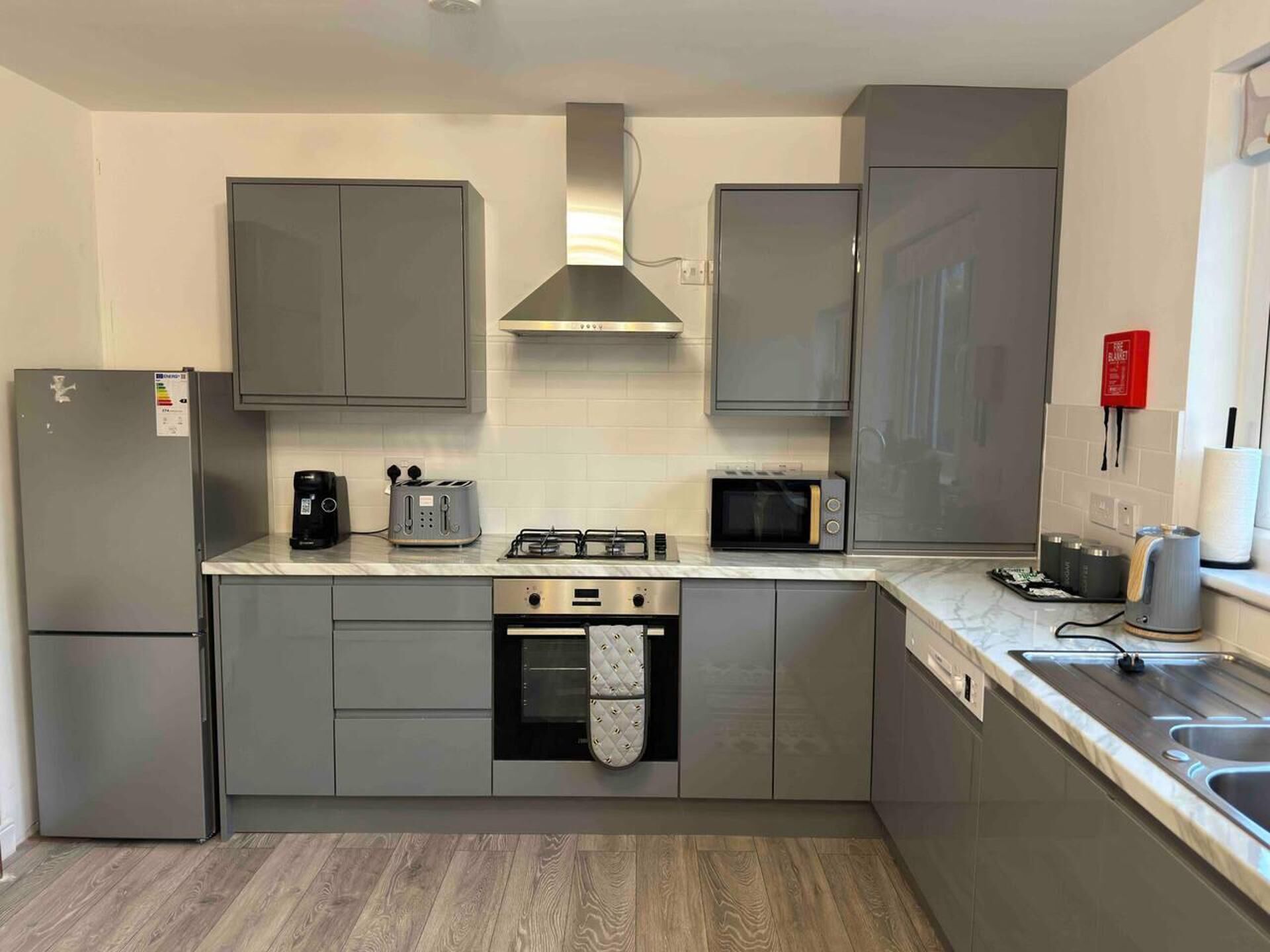 A modern kitchen with grey cabinets, a built-in oven, a microwave, and a gas stove.