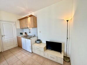 Compact kitchen with a modern design, featuring a stainless steel sink, microwave, and flat-screen TV.
