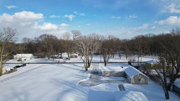 A snow-covered residential area with houses, a road, and trees.