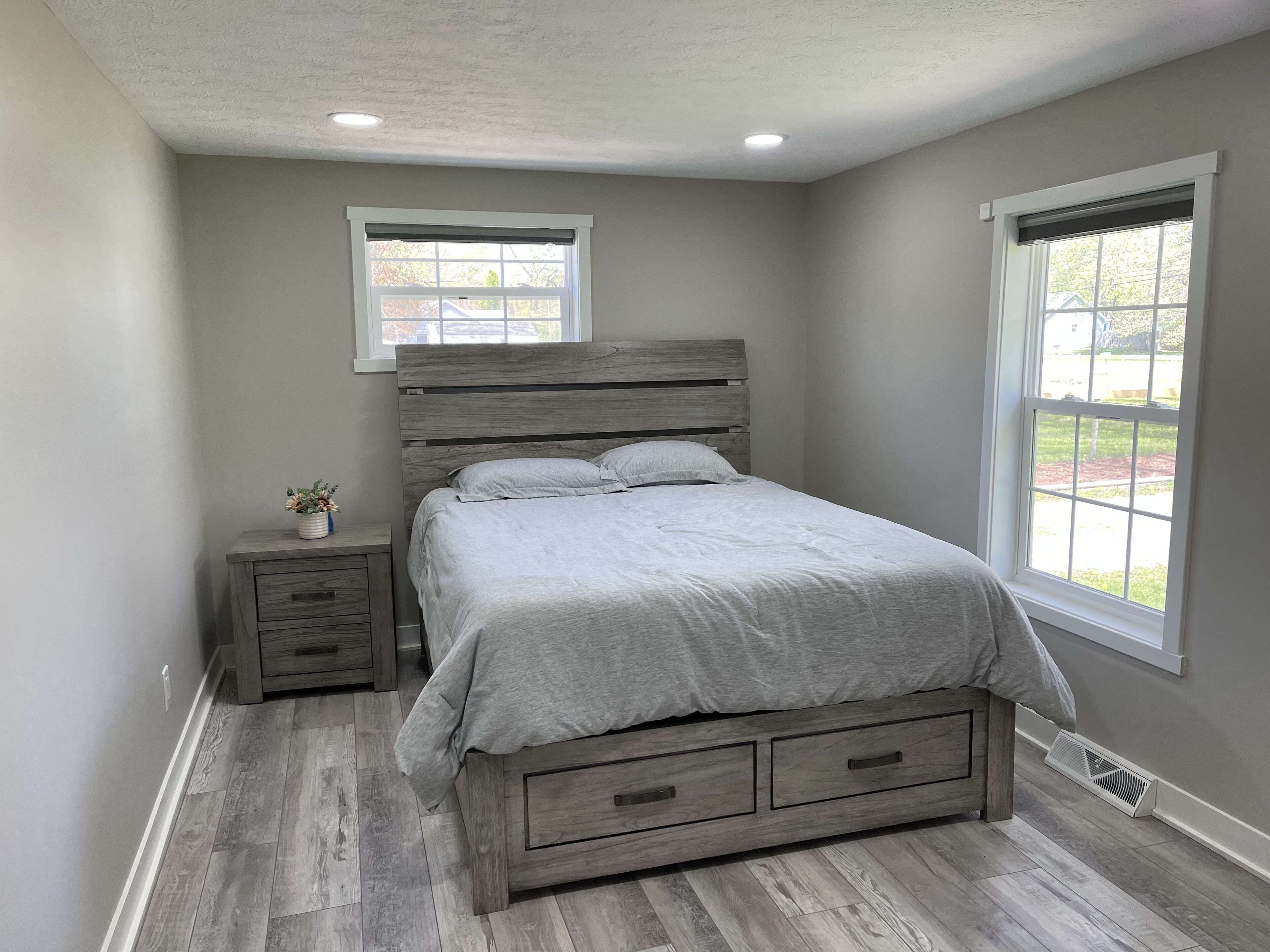 Un dormitorio con cama, mesitas de noche, un ventanal y vistas al exterior.