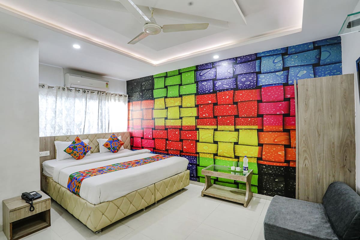 A bedroom with a bed, bedside table, and a colorful wall.