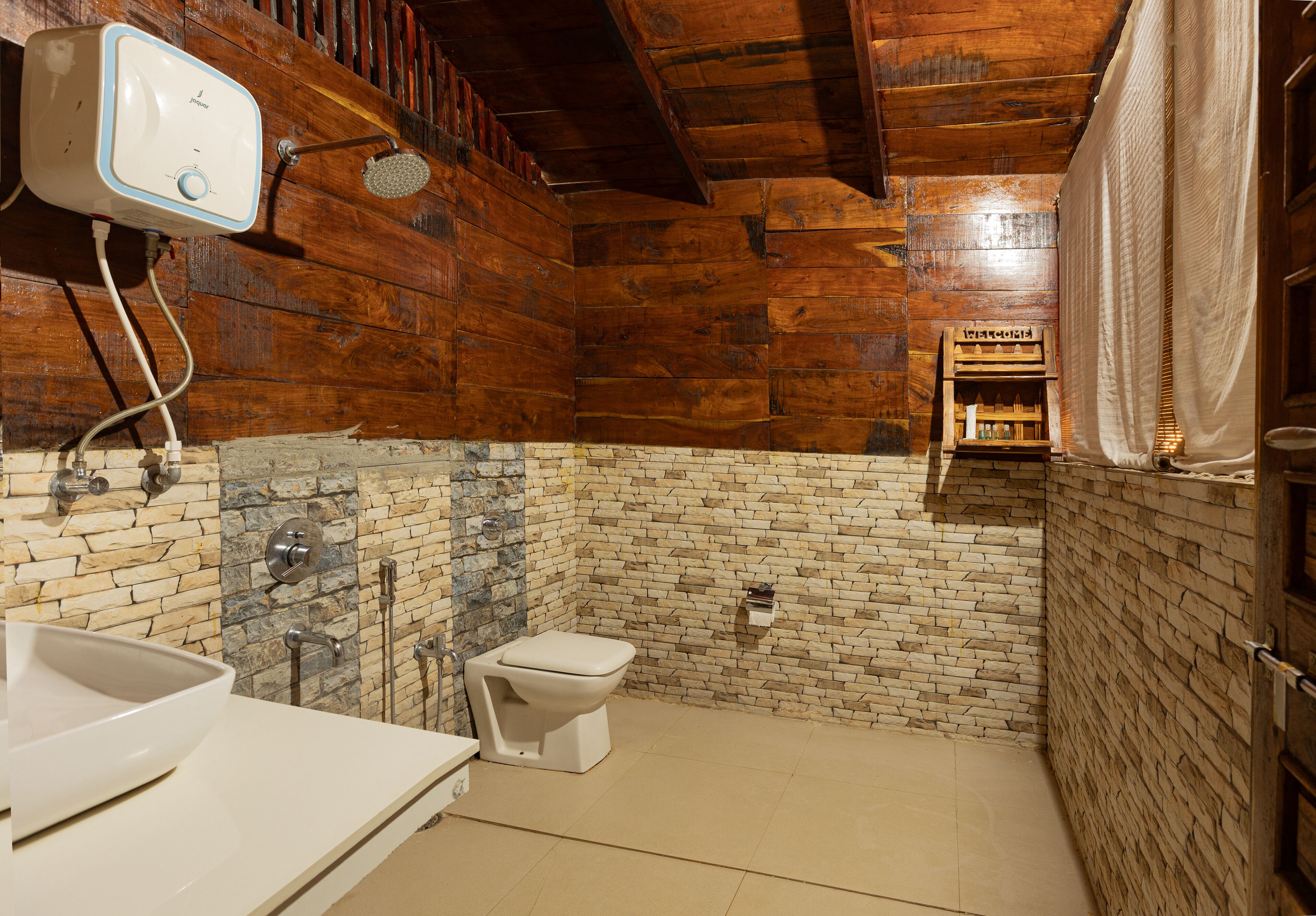 A bathroom with a wooden ceiling, a white toilet, a sink with a bowl, and a shower with a handheld showerhead.
