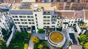A modern building with multiple floors, large windows, and a central courtyard with a circular green space. - Hostel van Gogh (Brussels)