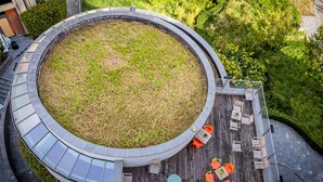 A circular outdoor area with a grassy center, surrounded by a paved walkway and seating areas with tables and chairs. - Hostel van Gogh (Brussels)