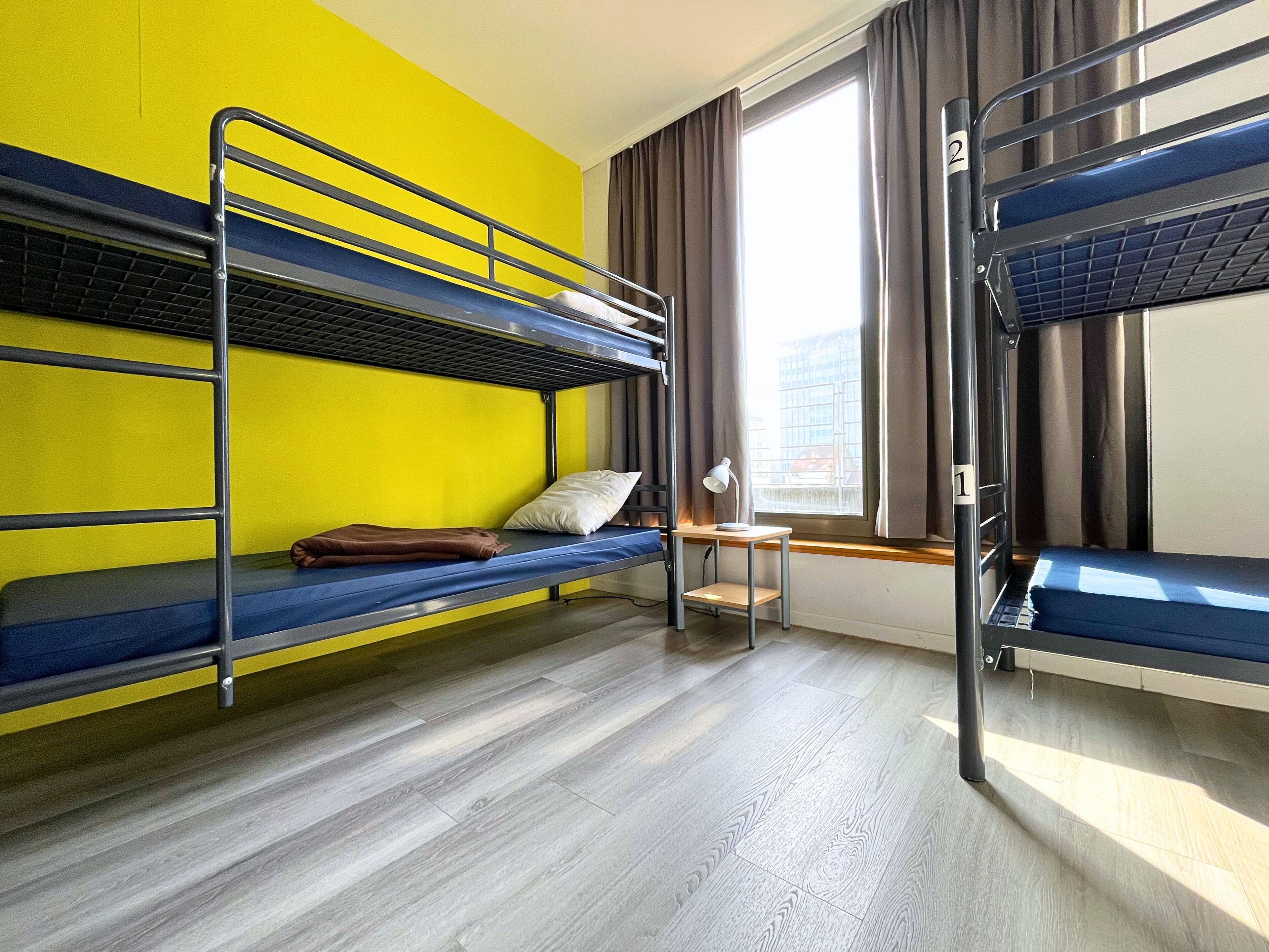 Un dormitorio con literas, un escritorio, una silla y una ventana con cortinas.